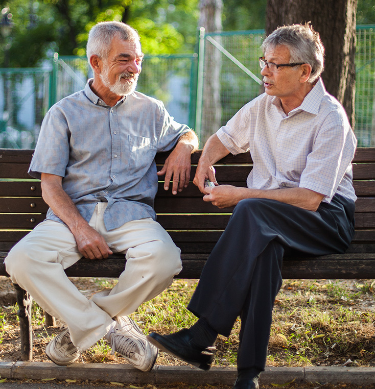 2 senior men sitting on a park bench talking