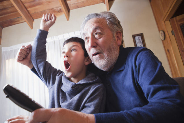 Grandfather and grandson cheering for sports game on television